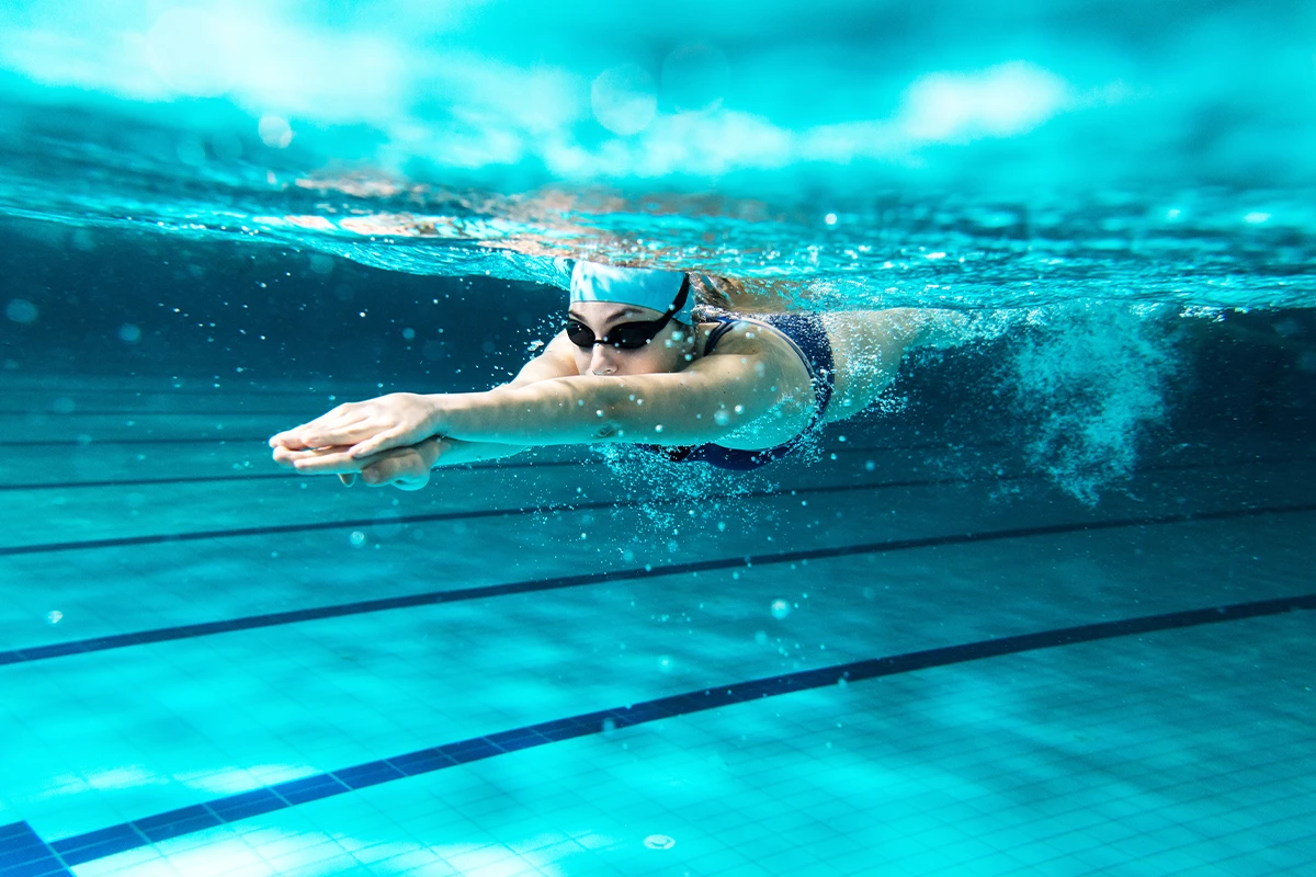 Unterwasseraufnahme einer Schwimmerin mit Badekappe und Schwimmbrille