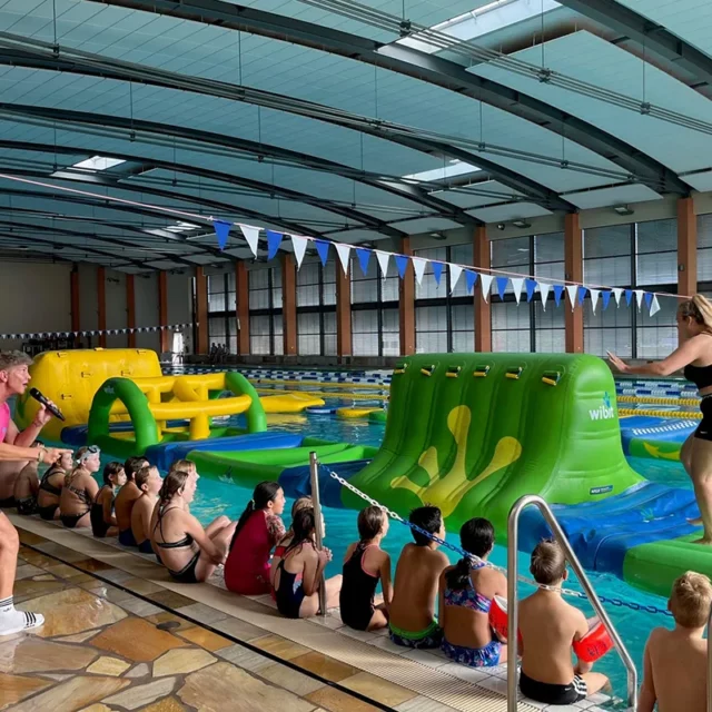 Die Animateurin von h2o fun events motiviert Erwachsene den Wasserparkour im Schwimmerbecken zu meistern