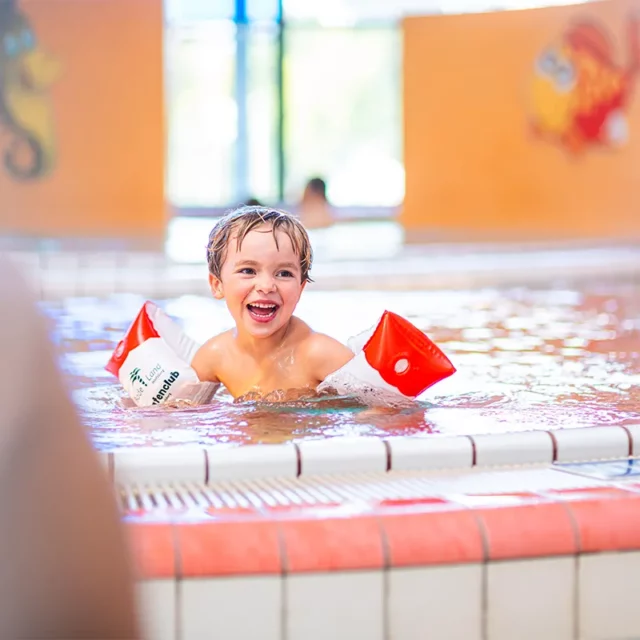 Lachender Junge mit Schwimmflügeln in unserem Kleinkinderbecken.