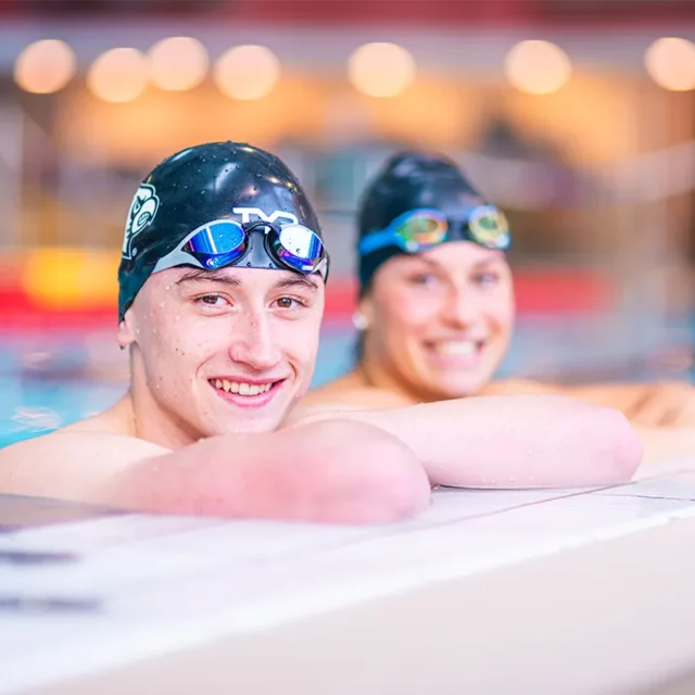 Portrait zweier Schwimmer, die sich am Beckenrand anlehnen.